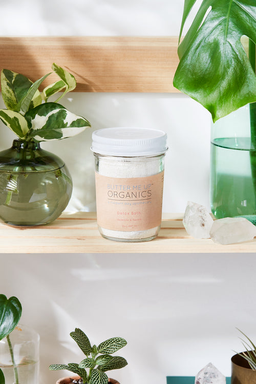 Detox bath Epsom salt clay essential oil soak with a bowl of white salts, green clay, and amber essential oils for relaxing self-care.